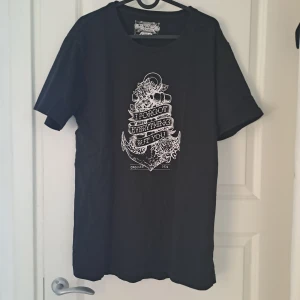Svart t-shirt från Crocker Jeans - Snygg svart t-shirt från Crocker Jeans med ett coolt vitt tryck på framsidan. Perfekt för en avslappnad stil. T-shirten har korta ärmar och en klassisk rund halsringning.