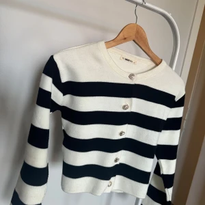 Randig kofta  - Säljer en snygg svartvit randig kofta. Koftan har långa ärmar och knappar framtill. Perfekt för en stilren look. Passar till både jeans och kjol!