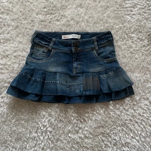 Jeanskjol med volanger - En lågmidjad jeanskjol omsydd från ett par jeans Midjemått tvärsöver - 39 cm Längd - 33cm