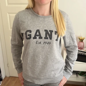 Grå sweatshirt från GANT - Säljer en klassisk grå sweatshirt från GANT med tryck framtill. Den är perfekt i storlek och har inte använts på ett bra tag!