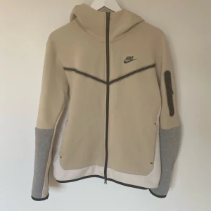 Nike Tech - Snygg beige Nike tech jacka. Jackan har en dragkedja framtill och en huva för extra skydd. 