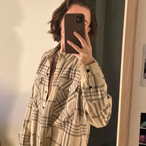 Beige rutig overshirt  - Säljer en beige rutig overshirt från dr denim. Skjortan har långa ärmar och knappar framtill. Perfekt för lager-på-lager-stil och en avslappnad look. Något tjockare bomullstyg. 