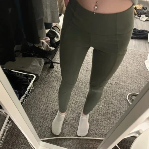 Gröna leggings från SOC - Säljer ett par gröna leggings från SOC i storlek S. De är högmidjade och har en tight passform, perfekta för träning. Materialet är syntetiskt och designat för att hålla dig torr och bekväm.
