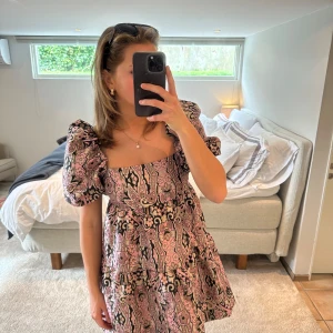 Blommig kortklänning med puffärmar - Världens sötaste klänning från &Other stories. Supersöt passform med puffärm och öppen rygg med rosa, svarta och guldiga detaljer. Den är helt oanvänd med lappen kvar. 💖🖤