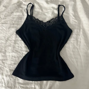 Svart linne med spetsdetaljer - Snyggt svart linne med smala axelband och vacker spetskant vid halsringningen. 