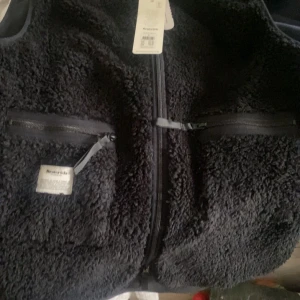 Svart fleeceväst från Resteröds - Säljer en svart fleeceväst från Resteröds med dragkedja framtill och två praktiska fickor med dragkedjor. 