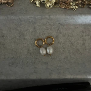 Guldörhängen med vita pärlor - Snygga små örhängen i guldfärg med hängande vita pärlor. Inte använda mycket eftersom jag redan har ett par liknade. Ena öronhänget är lite svårt att stänga men går absolut! Hör av dig för fler frågor eller bilder❤️