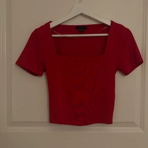 Röd och grön croppad topp från Amisu - Två stilrena croppade toppar från New Yorker , en i klarrött och en i mörkgrönt. Båda har fyrkantig halsringning och korta ärmar, vilket ger en modern och fräsch vibe. Materialet är mjukt och stretchigt, perfekt för att matcha med jeans eller kjol. Är i storlek M och L men passar perfekt på en person som har storlek S! Både två endast för 270