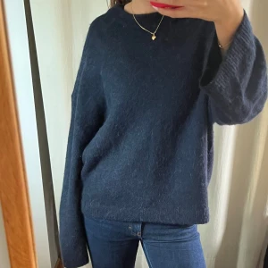 Mörkblå stickad tröja med loose fit - Säljer en mörkblå stickad tröja med loose fit och långa ärmar. Tröjan har en enkel, rund halsringning och är mjuk och skön i materialet. Perfekt för dig som gillar en chill och avslappnad stil. 
