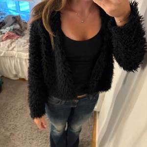 Svart pälsjacka från Gina Tricot - Fluffig svart pälsjacka från Gina Tricot i storlek M. Jackan har lång ärm, är kortare i modellen och har en riktigt mjuk och lurvig känsla. Perfekt för dig som vill sticka ut med en cool och trendig look.