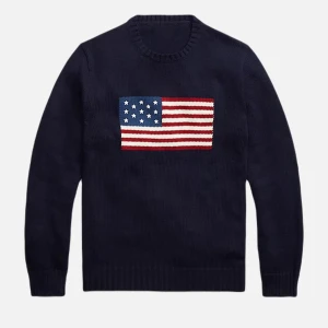 Mörkblå stickad tröja med USA-flagga - Snygg mörkblå stickad tröja från Ralph Lauren med en stor USA-flagga broderad på bröstet. Tröjan har rund hals och långa ärmar med ribbade muddar. Perfekt för dig som vill sticka ut med en klassisk och cool look.