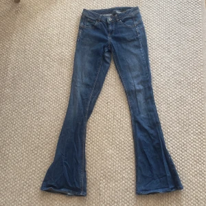 Blå flare jeans i storlek 27 - Snygga blå jeans med flare-ben och klassisk femficksdesign. Jeansen är lågmidjade tillverkade i ett stretchigt jeans material. Perfekt för dig som gillar moderna lågmidjade flare jeans💗💗.