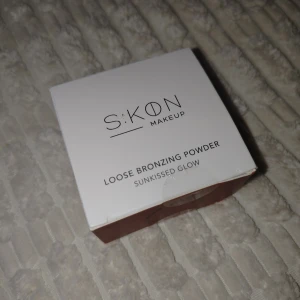 SKON Loose Bronzing Powder - Ny och oanvänd löst bronzer i nyansen Sunkissed Glow från SKON Makeup. Ger en naturlig, solkysst look med lätt mineralformula. Perfekt för att addera värme och lyster till ansiktet. Innehåller 5 g och passar alla hudtoner.