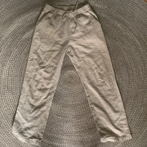 Beige linnebyxor från Kappahl, strl 164 - Snygga beige linnebyxor från Kappahl i storlek 164. Byxorna har resår och snörning i midjan samt sidfickor. Perfekta för en chill och avslappnad stil, tillverkade i svalt linnematerial.