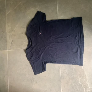 GANT T-shirt – storlek 170 - Mörkblå GANT T-shirt i storlek 170, tillverkad i mjukt och bekvämt material. Klassisk passform med liten broderad logga på bröstet. Obs: Har ett litet minihål (se bild 5) men det syns inte vid användning.💰 Pris: 100 kr Sökord: gant, t-shirt, t shirt, tshirt, blå t-shirt, mörkblå, logga, ungdom, herr, dam, unisex, storlek 170, gant tröja, kortärmad, märkes t-shirt, casual, basplagg