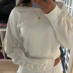 Vit sweatshirt med rynkade ärmar Lindex - Säljer en vit sweatshirt från Lindex med coola rynkade detaljer längs ärmarna. Tröjan har rund hals. Använd ett par gånger men fint skick!!💕
