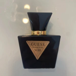 Guess Seductive Noir parfym - Guess Seductive Noir är en blommig parfym i en elegant svart flaska med guldiga detaljer och trekantig etikett. Doften har toppnoter av bergamott och pion, hjärtnoter av jasmin, liljekonvalj och iris samt basnoter av vanilj, vetiver och läder. Rymmer cirka 90% kvar då den ej kommer till användning längre. Köpt på Zalando för 150kr, originalförpackning följer ej med!