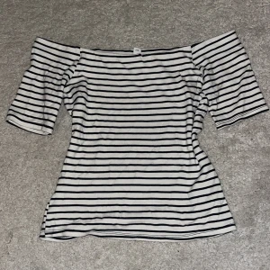 Randig offshoulder topp  - Säljer en vit och svart randig offshoulder topp med trekvartsärm. Den har en figurnära passform. Inga defekter 💞