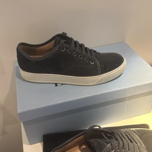 Lanvin sneakers i grå mocka uk6 - Snygga sneakers från Lanvin i mörkgrå mocka med vit sula och glansig svart tå. Klassisk låg modell med snörning och rund tå. Lyxig känsla med skinnfoder och stilren design som sticker ut med den lackade tån. Bara skor. Skick 10/10