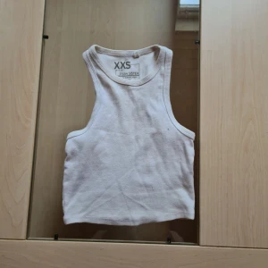 Vit ribbad linnetopp  - Säljer en enkel och stilren vit ribbad linnetopp från FSBN Sister i storlek XXS. Toppen har klassisk rak passform och breda axelband, perfekt för lager-på-lager eller till jeans. Materialet är mjukt och stretchigt för en bekväm känsla. Förekommer dock lite fläckar som går bort I tvätten. Går att köpa 3-pack (kolla mina annonser)