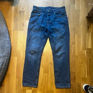 Blå raka jeans från Zara, strl 40 - Klassiska blå jeans från Zara i rak modell med fem fickor och normal passform. Jeansen har en snygg mörkblå tvätt och är tillverkade i bomullsdenim. Perfekta för en clean och stilren look.