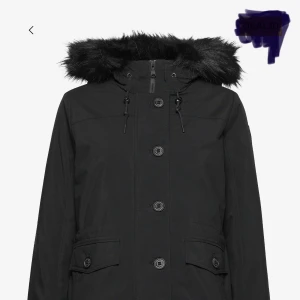 Svart vindjacka från Gant - Svart vindjacka från Gant med klassisk design, knappar och dragkedja framtill samt snörning i midjan. Jackan har två stora fickor med lock och ribbade muddar vid ärmsluten. Perfekt för dig som gillar stilren och funktionell look.