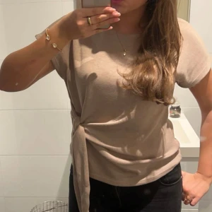 Beige topp med knyt från Zara - Superfin beige topp från Zara med korta ärmar och snygg knytning i sidan🤎🤍Pris kan diskuteras