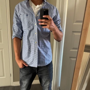 Blårutig skjorta från IZOD slim fit - Snygg blårutig skjorta från IZOD i slim fit-modell. Skjortan är storlek M och slimfit, den passar perfekt på mig som är 180cm och 75kg. 10/10 skick. Tveka inte att ställa frågor💯