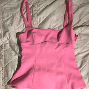 Rosa korsettopp från Zara  - Supersnygg rosa korsettopp med breda axelband och en cool cut out-detalj i ryggen. Toppen har figurnära passform och lätt utsvängd nederkant. Perfekt för dig som vill sticka ut med en färgstark och trendig look.