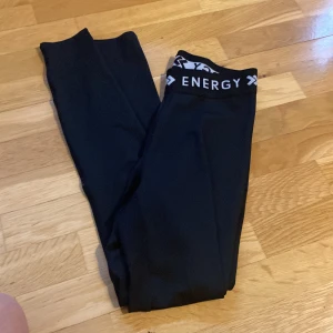 Svarta leggings från 157 Energy - Svarta leggings från 157 Energy med bred resår i midjan där det står 'ENERGY'. Snygg och sportig look, perfekta för träning eller chill. Stretchigt material som sitter tajt och bekvämt.