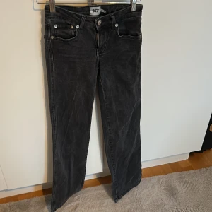 Svarta jeansbyxor från 157, XXS - Snygga svarta jeansbyxor från 157 i storlek XXS. Modellen har raka/bootcut ben, klassiska femficksdetaljer och coola bakfickor med lock och knapp. Jeansen har en mörk tvätt och full längd, perfekta till sneakers eller boots.