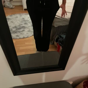 Svarta Juicy Couture byxor  - Svarta mjukisbyxor från Juicy Couture i mjuk velour med raka ben och bred resår i midjan. Byxorna har två bakfickor med lock och silverfärgade knappar samt diskret JC-broderi. Perfekta för en chill och snygg look.