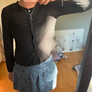 Svart kofta med broderier  - Svart kofta med knappar framtill och snygga broderier över axlar och bröst. Långärmad och i tunnare material som känns skönt mot huden. 