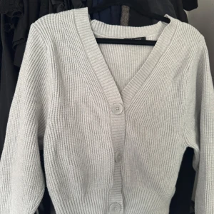 Ljusgrå ribbad kofta Gina Tricot - Superfin ljusgrå ribbad kofta från Gina Tricot i storlek XS. Koftan har v-ringning, stora knappar framtill och är stickad i ett mjukt material. Koftan är använd ett fåtal gånger!!💞Inga hål eller fläckar finns!🤍