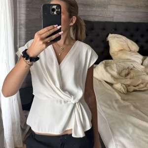 Vit omlottopp med knyt i midjan - Säljer en vit topp från Zara med knytning i midjan. Toppen är knappt använd där av säljer jag den💖