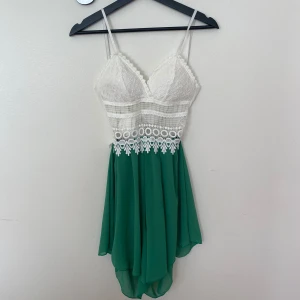 Vit och grön spets jumpsuit med rosett - Superfin kort byxdress med vit spets upptill och grön, flowy kjol. Smala axelband och snygg knytning i ryggen. Använd 1 gång.