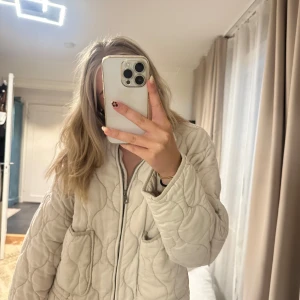 Quiltad vit jacka från Zara - Quiltad vit jacka från Zara i storlek M. Jackan har en loose passform, dragkedja framtill och två stora fickor. Snyggt mönstrad med vågiga sömmar och tillverkad i mjukt bomullstyg. Perfekt för lager-på-lager och chill stil. Passar även en S. Se bilder för fläckar och den är lite nopprig❤️