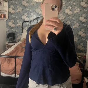 Mörkblå v-ringad topp - Säljer denna jättefina mörkblåa v-ringade toppen från Gina tricot. Den har knytband runt midjan och utsvängda ärmar. Använd fåtal gånger och är  i nyskick💙