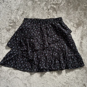 Blommig volangkjol från Stradivarius - Supersöt svart kortkjol från Stradivarius med små blommor i blått, rosa och vitt! Pris kan diskuteras🩷