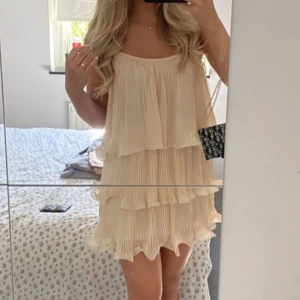 Plisserad ljusbeige volangklänning - Supersöt trending kort plisserad klänning från h&m.