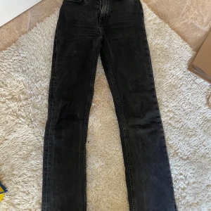 Svarta jeans med slits nertill - Säljer ett par svarta jeans med raka ben och snygg slits vid benslutet. Jeansen har hög midja och klassisk femficksdesign. Perfekta till sneakers eller boots för en chill look.