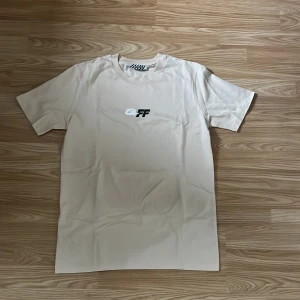 Beige Off-White t-shirt med tryck - Snygg beige t-shirt från Off-White med svart och vitt logotryck på bröstet och stort grafiskt motiv på ryggen. Klassisk rund hals och korta ärmar. Tillverkad i mjuk bomull med lite stretch för extra komfort.