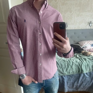 Rödvit rutig skjorta från Polo Ralph Lauren - Säljer en rödvit rutig skjorta från Polo Ralph Lauren i slim fit-modell. Skjortan har långa ärmar, klassisk krage och knappar framtill. Tillverkad i stretchig bomull för extra komfort samt den ikoniska broderade loggan på bröstet. Perfekt för en stilren look till sommaren! 