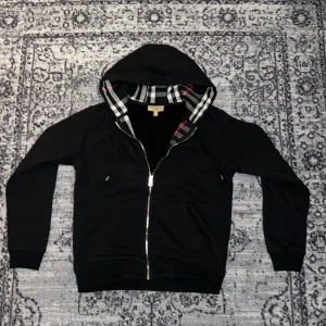 Burberry hoodie Svart - Säljer en svart hoodie från Burberry. Jag har knappt använt hoodien, den är i nytt skick. Det står L i hoodien men den är liten i passformen så jag säljer den som M/S.