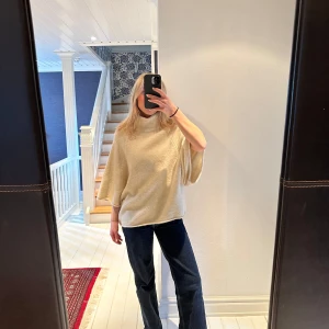 Beige stickad ponchotröja med polokrage - Säljer en beige stickad ponchotröja med polokrage. Tröjan har vida trekvartsärmar och en lös passform. Frakt spårbar PostNord tillkommer 59 kr. 