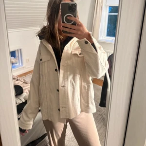 Vit overshirt i manchester - Säljer en vit overshirt i manchester med knappar framtill och klassisk krage. Jackan har två bröstfickor och lång ärm, 