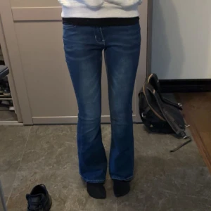 Blå bootcut jeans - Säljer ett par klassiska blå bootcut jeans med snygg tvätt och vita sömmar. Jeansen har normal passform och är tillverkade i denim med stretch för extra komfort. Perfekta för dig som gillar en tidlös stil med lite utsvängda ben.