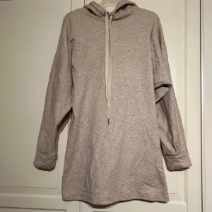 Beige hoodieklänning med luva - Säljer en beige hoodieklänning med luva och långa ärmar, tillverkad i mjukt bomullsmaterial i strl S