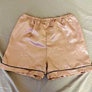 Pyjamas shorts - Snygga rosa pyjamas shorts i satin med elastisk midja och svart kant längst ner.  
