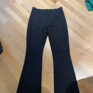 Svarta bootcut kostymbyxor hm - Snygga svarta kostymbyxor med bootcut passform och normal midja. Byxorna har klassisk design med knapp och dragkedja framtill. Perfekta för en stilren look.